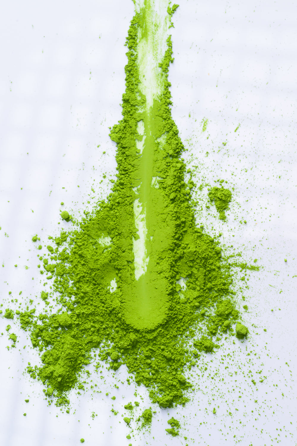 Close-up of fine green matcha powder spread across a white surface.