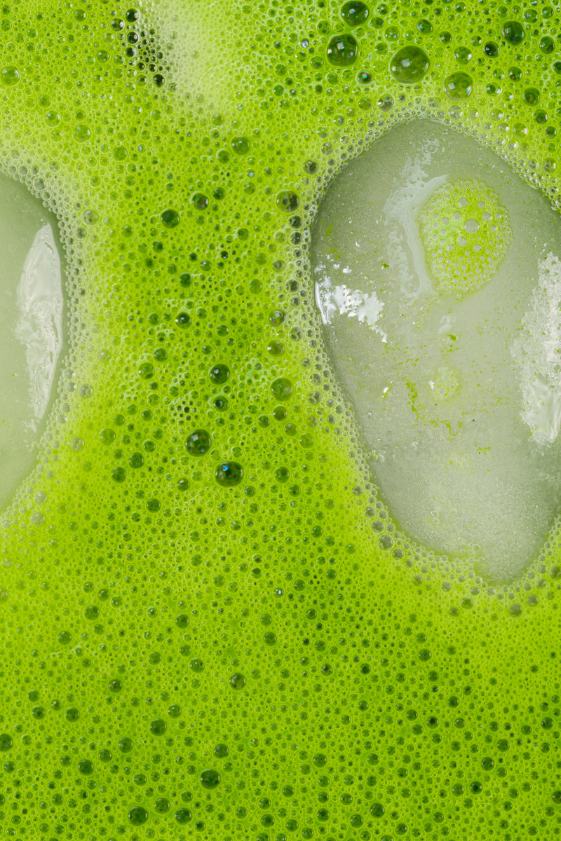 Close-up of iced matcha foam and bubbles.