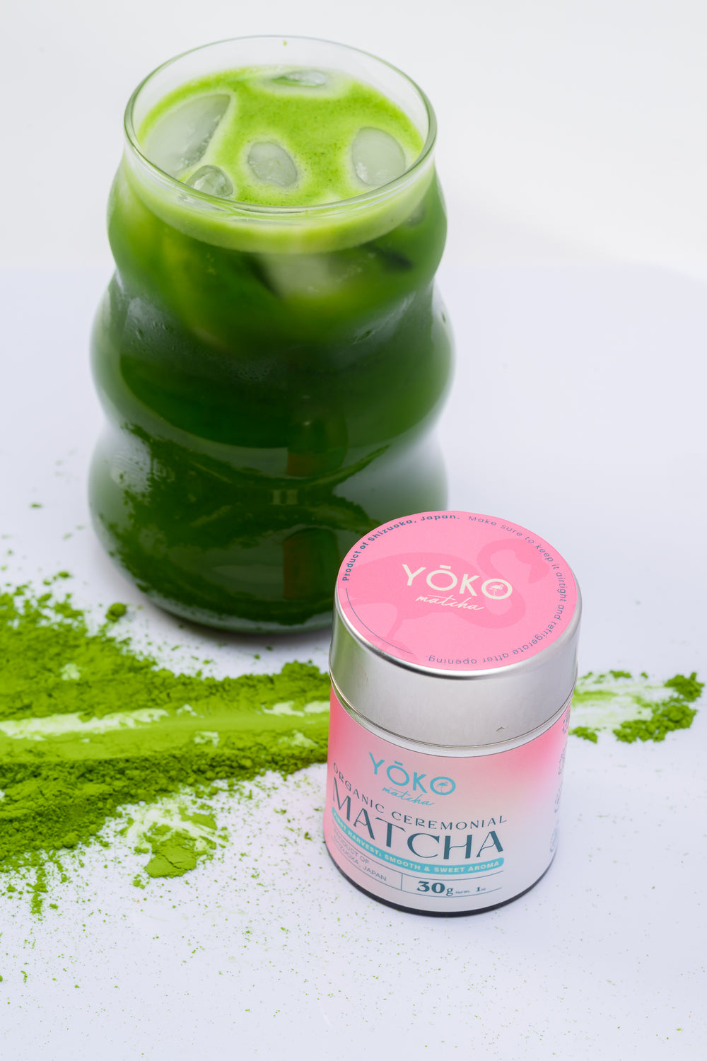 Iced green matcha beside a 30g tin of Yōko Matcha organic ceremonial matcha.